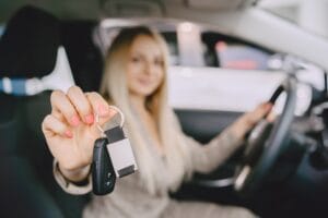 Mujer recibiendo las llaves de su carro nuevo tras conseguir seguro de auto sin licencia en Estados Unidos