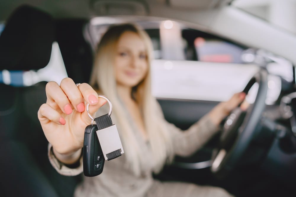 Mujer recibiendo las llaves de su carro nuevo tras conseguir seguro de auto sin licencia en Estados Unidos